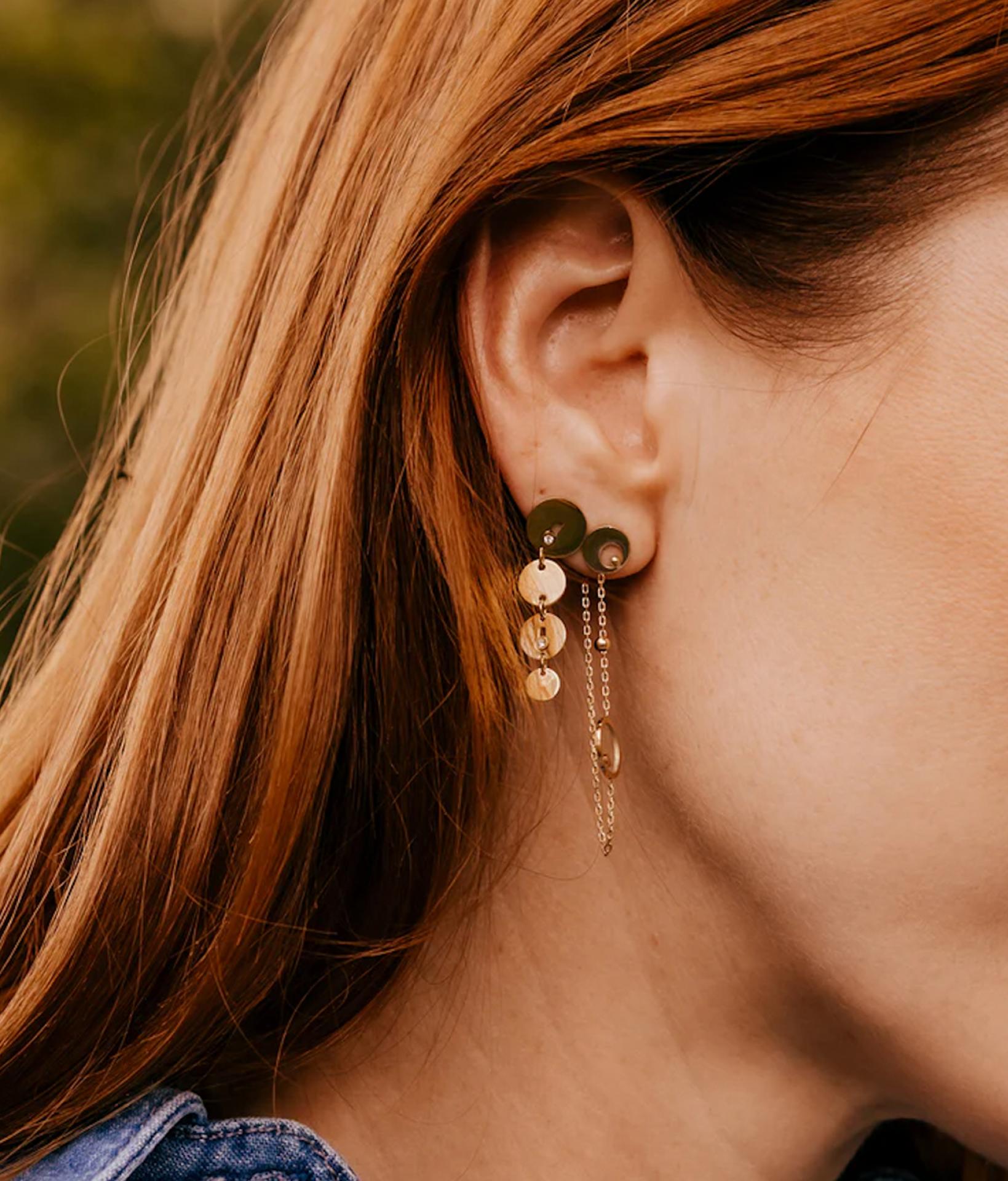 junge Frau seitliche Sicht auf die Ohren, die einen goldenen haengenden Ohrstecker von Zag Bijoux trägt 