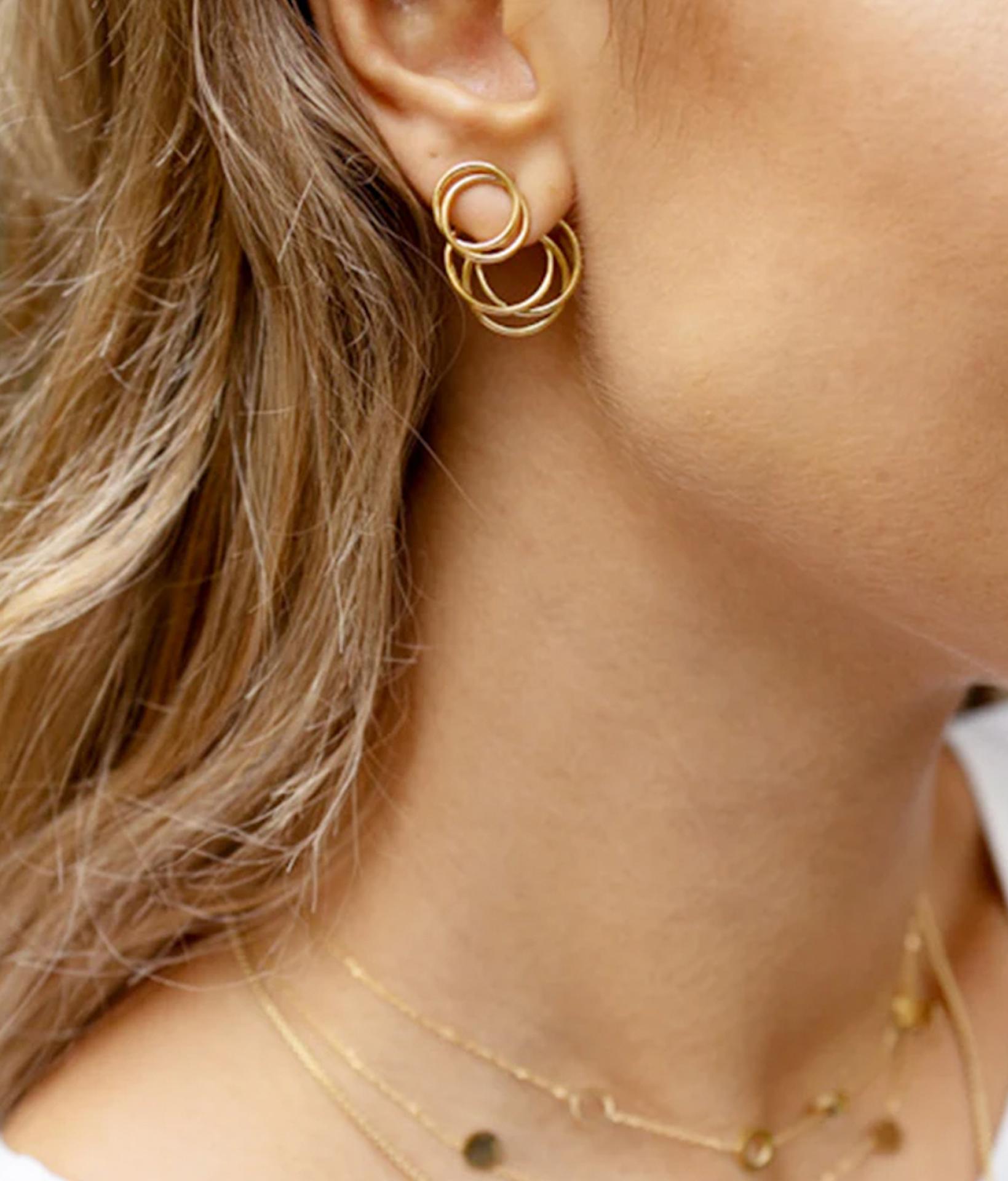 junge Frau mit blonden Haaren und seitlichen Profil trägt zweiteilige ohrstecker von Zag Bijoux aus goldenen Ringen