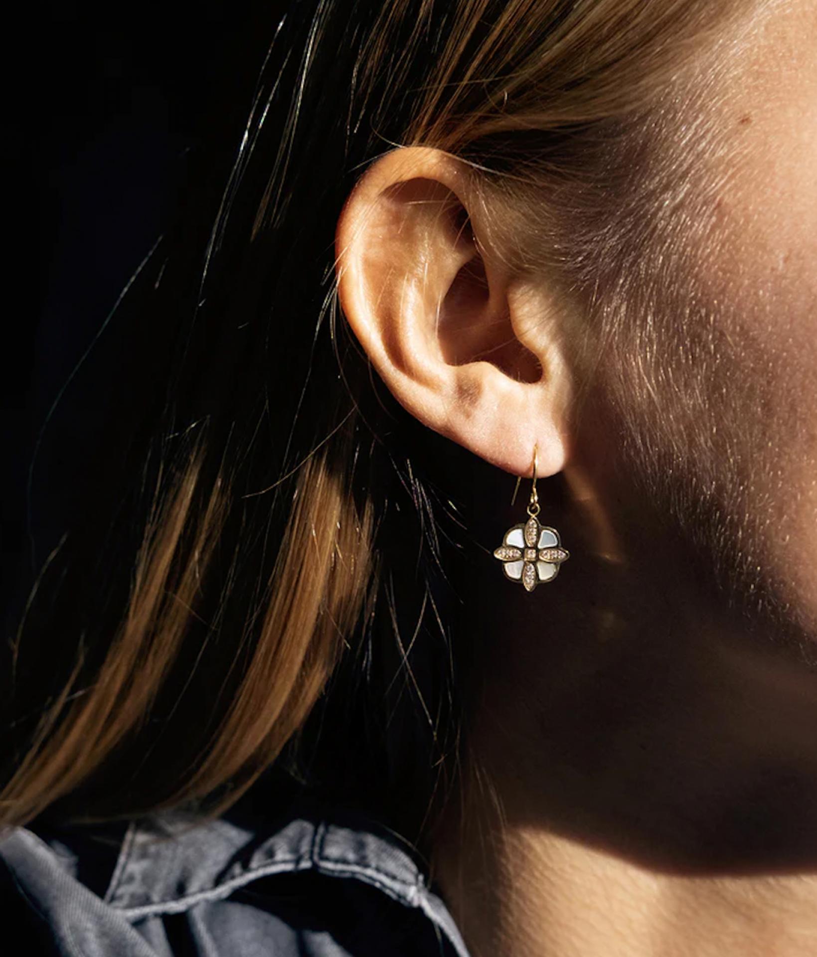 Nahaufnahme von einer jungen Frau die Ohrringe in Blumen-Form aus Perlmutt und Steinen trägt