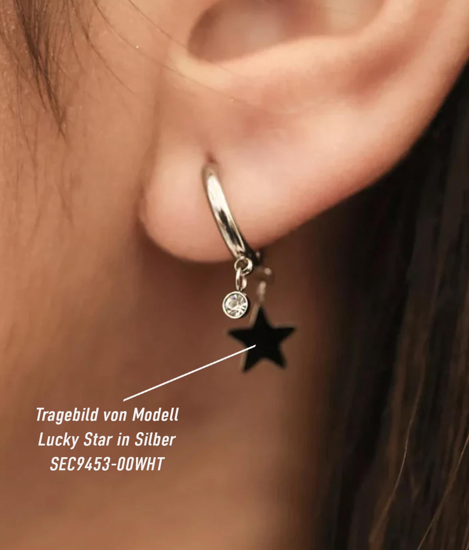 Ohr von einer jungen Frau trägt kleine silberne Creolen-Ohrringe mit einem Stern Anhänger