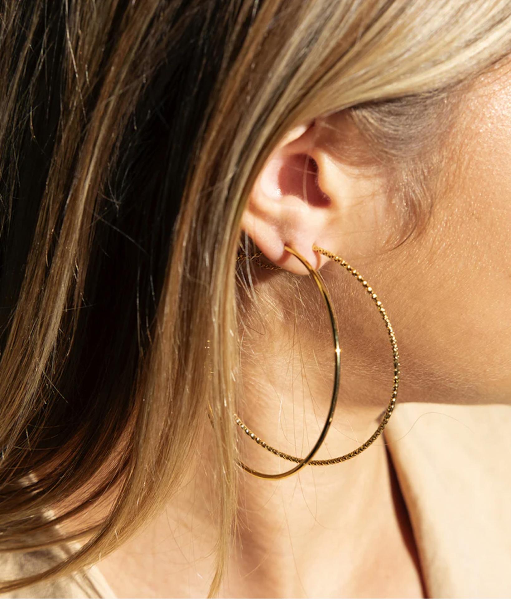 blondes Model mit seitlichem Profil trägt 6cm große goldene Creolen aus geklopftem vergoldeten Edelstahl 